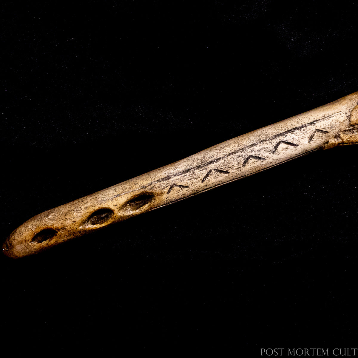Close-up of the Mas d’Azil spearthrower replica showing the engraved geometric markings, perforations and aged antler-style surface.