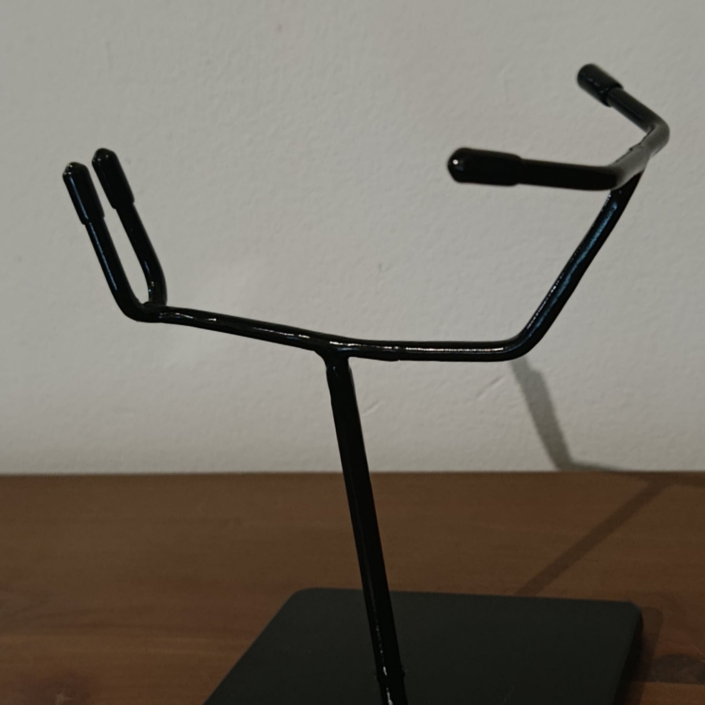 Minimalist skull support structure in black gloss metal, designed to hold skulls without mandible while preserving anatomical alignment and visual balance.