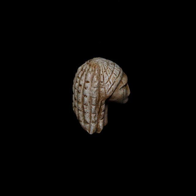 Side view of the Venus of Brassempouy replica showing the facial profile and distinctive engraved head pattern of the Gravettian figurine.