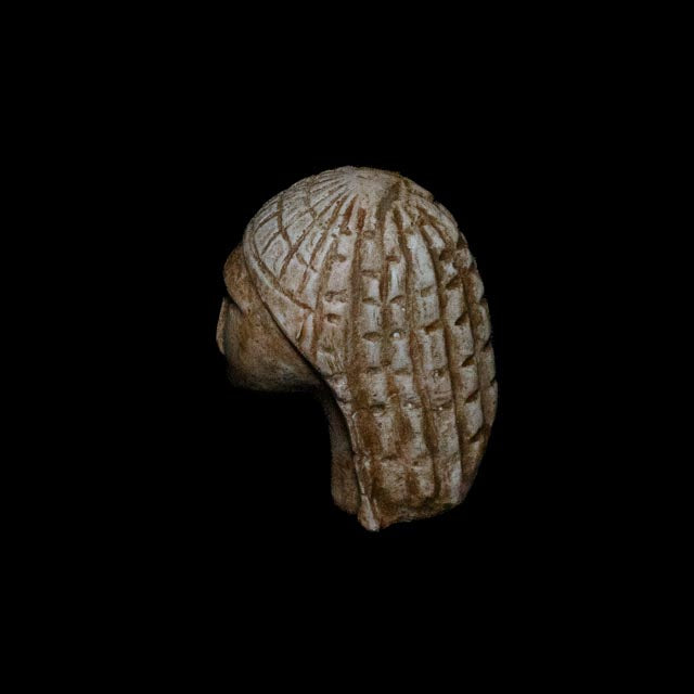 Three-quarter rear view of the Brassempouy Paleolithic figurine showing the deeply incised pattern and hand-applied aged patina.